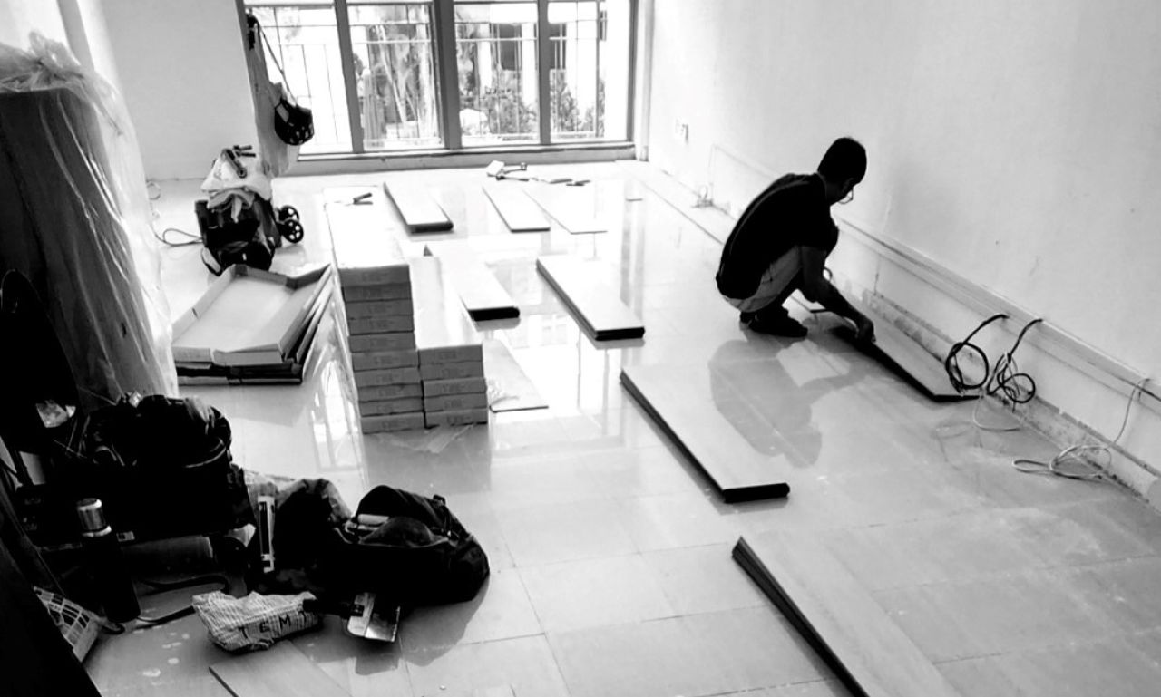 Worker laying floor tiles, with multiple floor tiles laying around